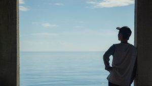 person-contemplating-ocean-view-through-window-frame