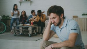 lonely-man-sitting-amidst-social-gathering